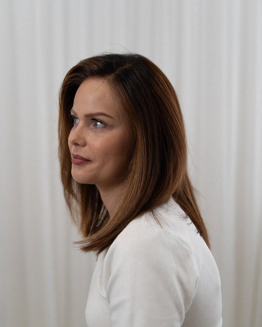 Woman in a white shirt standing against a white curtain